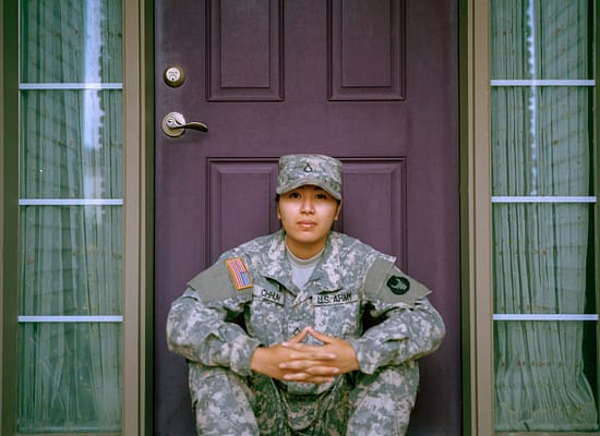 Latina Army Veteran sitting on her doorstep.